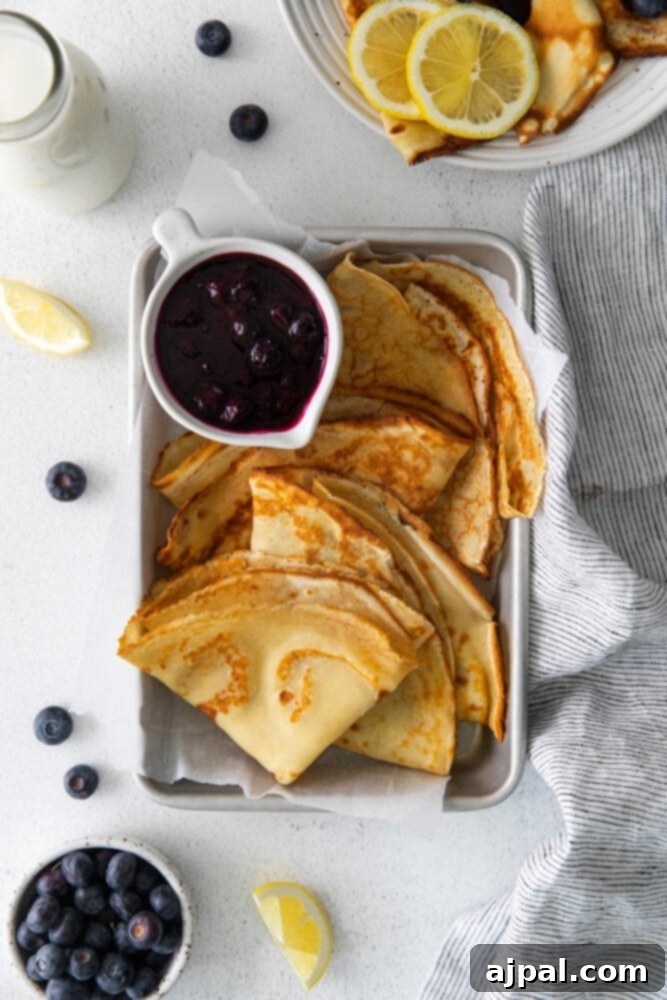 Close-up of fluffy lemon blueberry crepes with a generous serving of blueberry sauce.