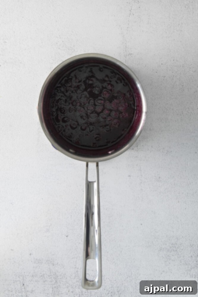 Rich blueberry sauce simmering in a metal pan, ready to become the delicious filling.