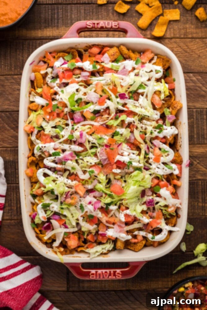 frito pie casserole with lettuce and sour cream in a dish