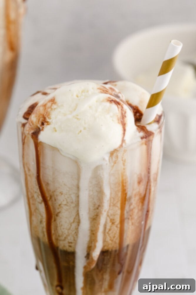 Guinness Baileys Float Delight 4 Guinness float in a glass with a gold paper straw and chocolate syrup
