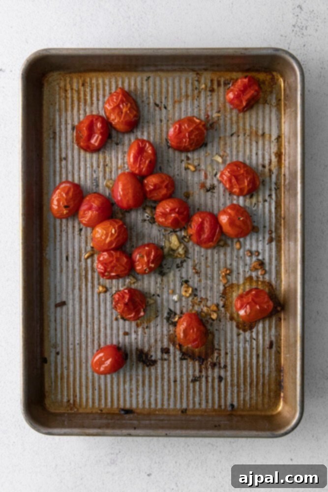 Creamy Goat Cheese and Roasted Tomato Pasta 5 Bright red cherry tomatoes are artfully arranged on a parchment-lined baking sheet, glistening with a drizzle of olive oil and a sprinkle of fresh herbs, poised for roasting in a warm oven.
