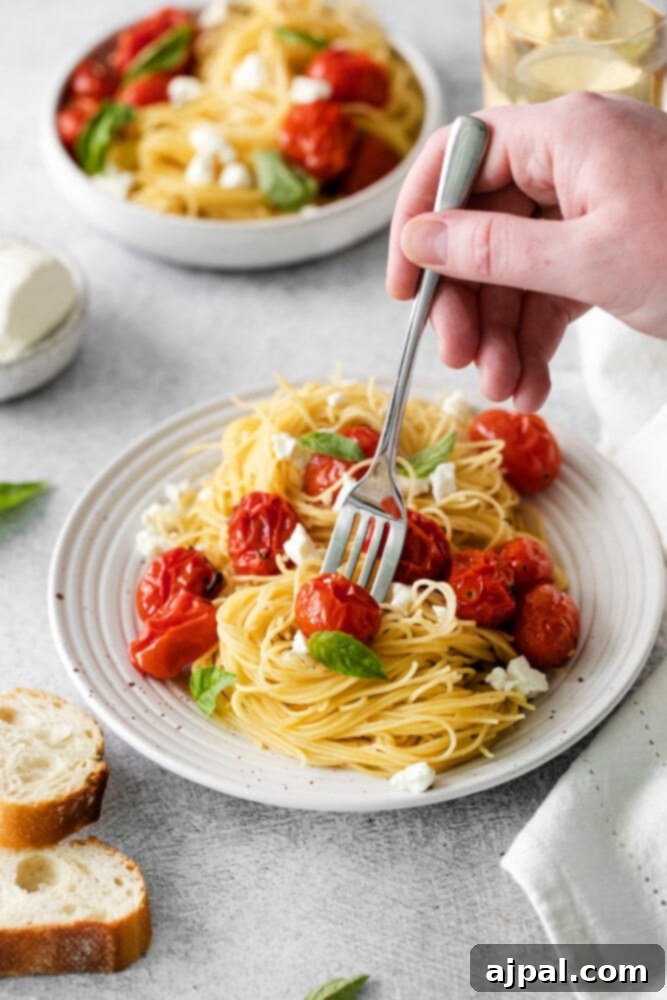 Creamy Goat Cheese and Roasted Tomato Pasta 8 A person is shown enjoying a plate of roasted tomato and goat cheese pasta, with a fork lifting some strands, ready to eat.