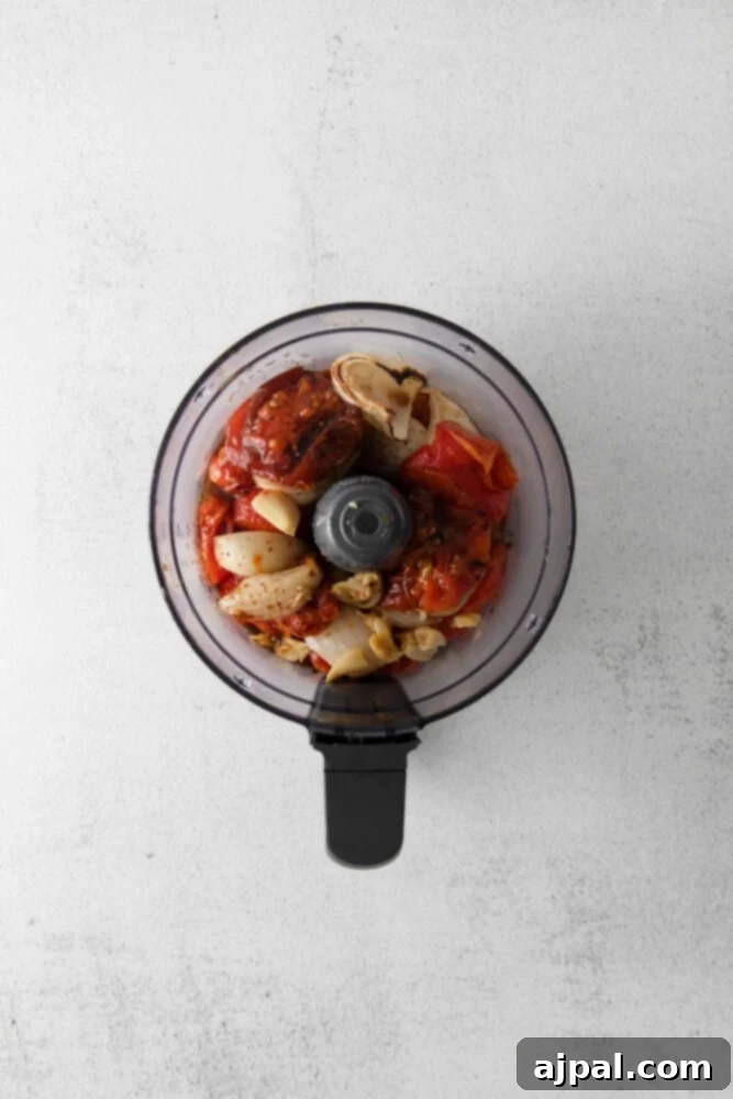Deep Roasted Tomato Marinara 7 Roasted tomatoes and onions being transferred into a food processor for blending.