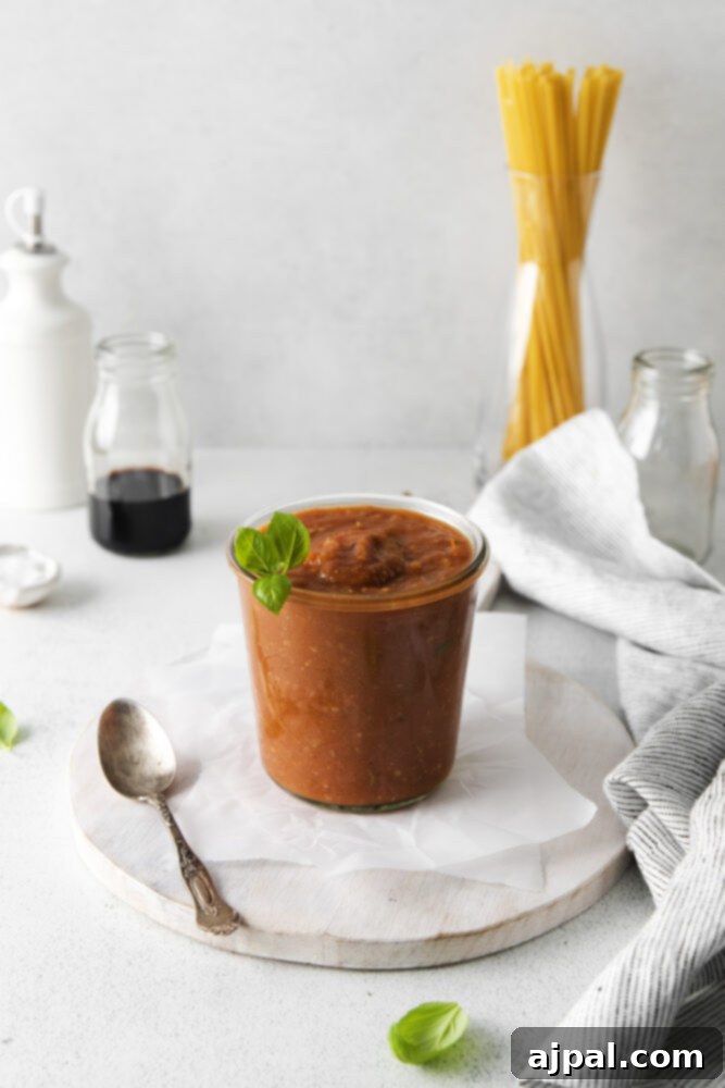 Deep Roasted Tomato Marinara 9 A simple white bowl filled with freshly made roasted tomato marinara sauce on a matching white plate.