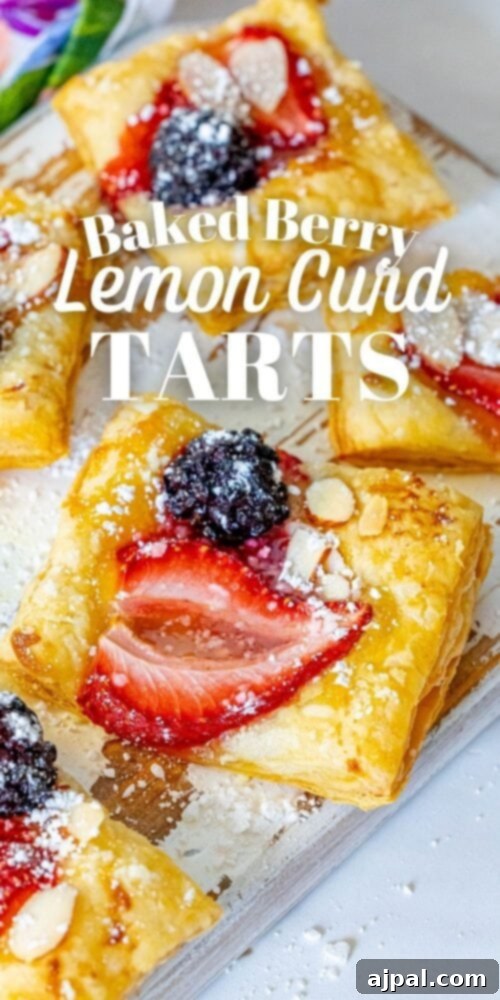 Bright Lemon Berry Tarts 15 Picture of a perfectly baked lemon curd tart on a baking sheet, topped with an almond, strawberry, and blackberry.