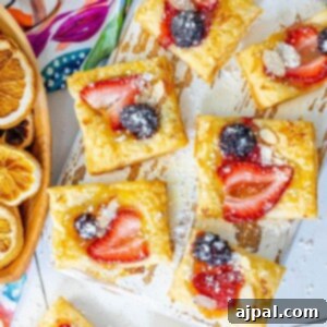 Picture of a baked lemon curd tart on a baking sheet with an almond, strawberry, and blackberry on top