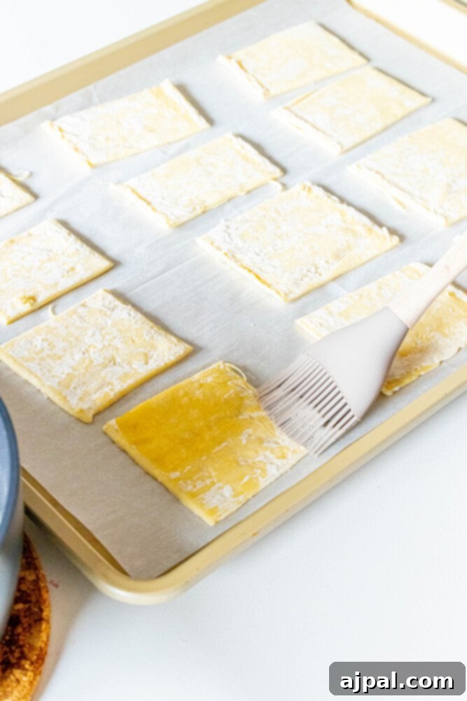 Bright Lemon Berry Tarts 4 Image showing puff pastry squares being brushed with melted butter, an essential step for a golden crust.
