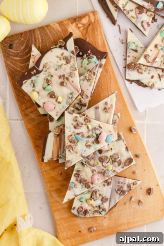 white and dark chocolate bark with m&ms in it on a wooden cutting board