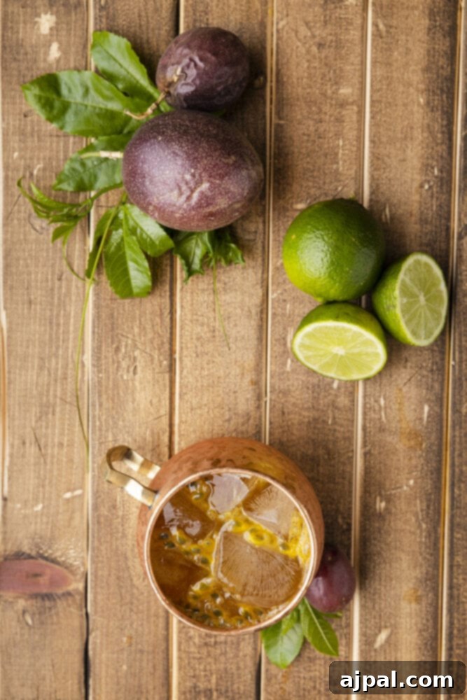Dark Tropics Tempest 12 A copper mug with a Passion Fruit Dark and Stormy, garnished with mint and a lime slice, on a rustic wooden table.