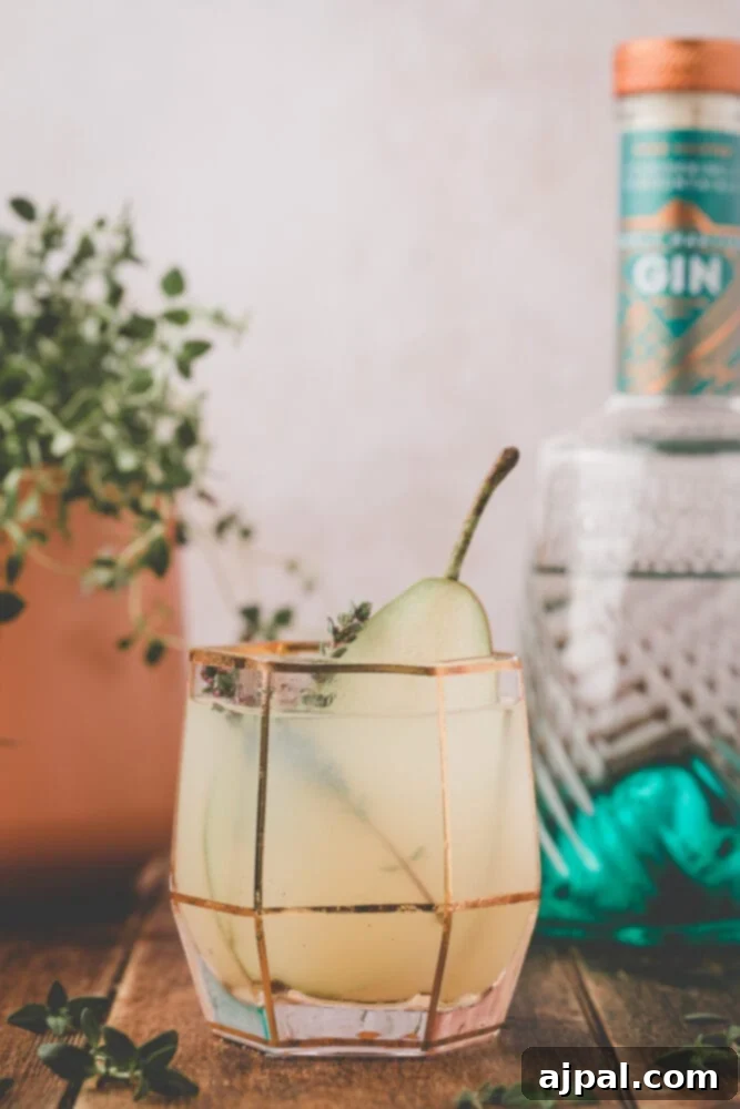 Golden Pear Fizz 2 gin fizz cocktail in a glass with a slice of pear in it