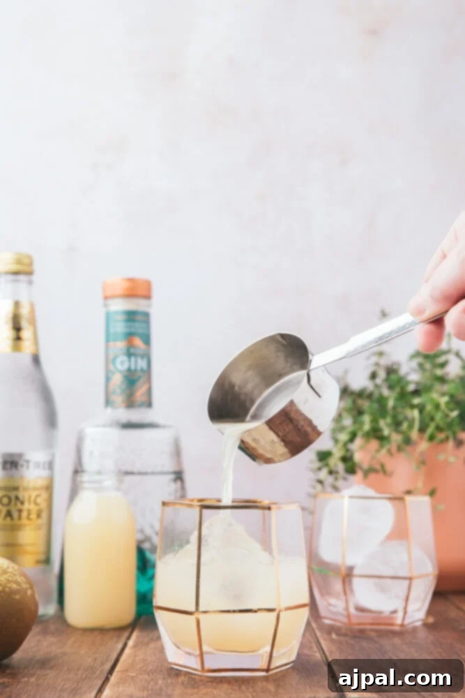 Golden Pear Fizz 7 picture of a hand pouring simple syrup into a glass