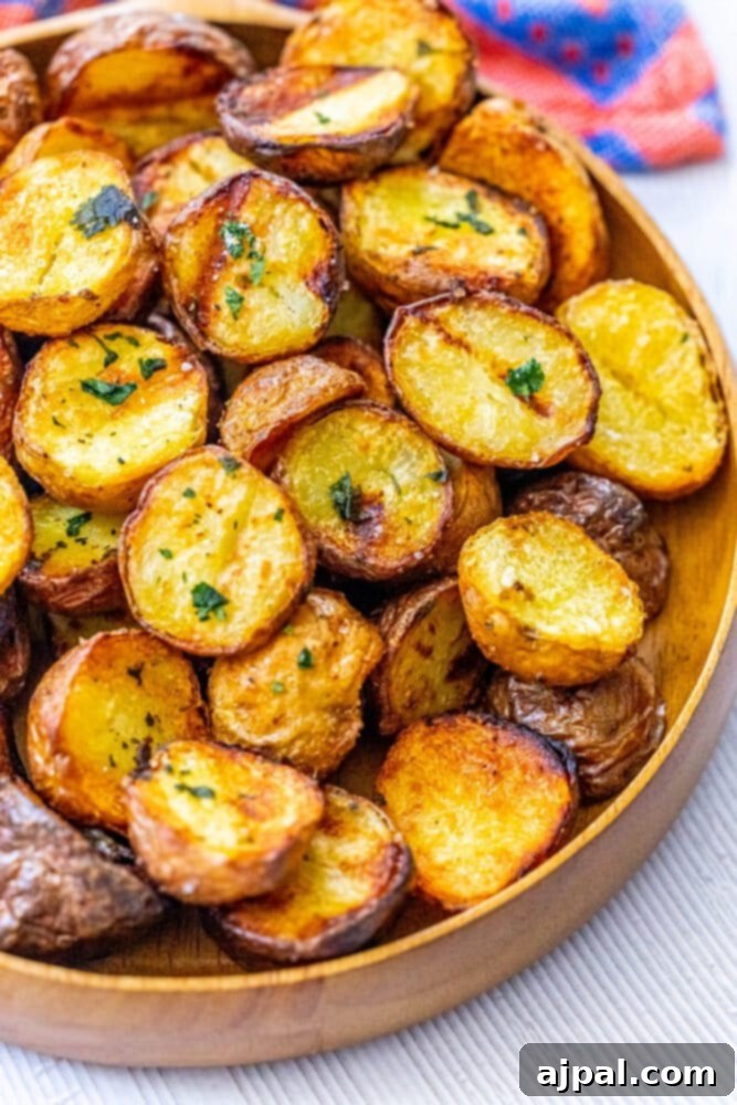 Close-up of golden-brown grilled potatoes on a rustic wooden platter, garnished with fresh herbs and a sprinkle of sea salt.