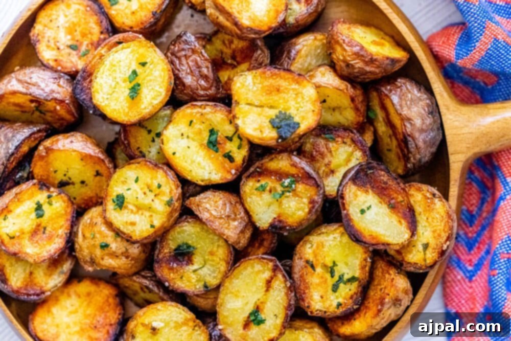 A wooden platter filled with crispy, golden-brown grilled potatoes, garnished with fresh herbs and a sprinkle of salt.
