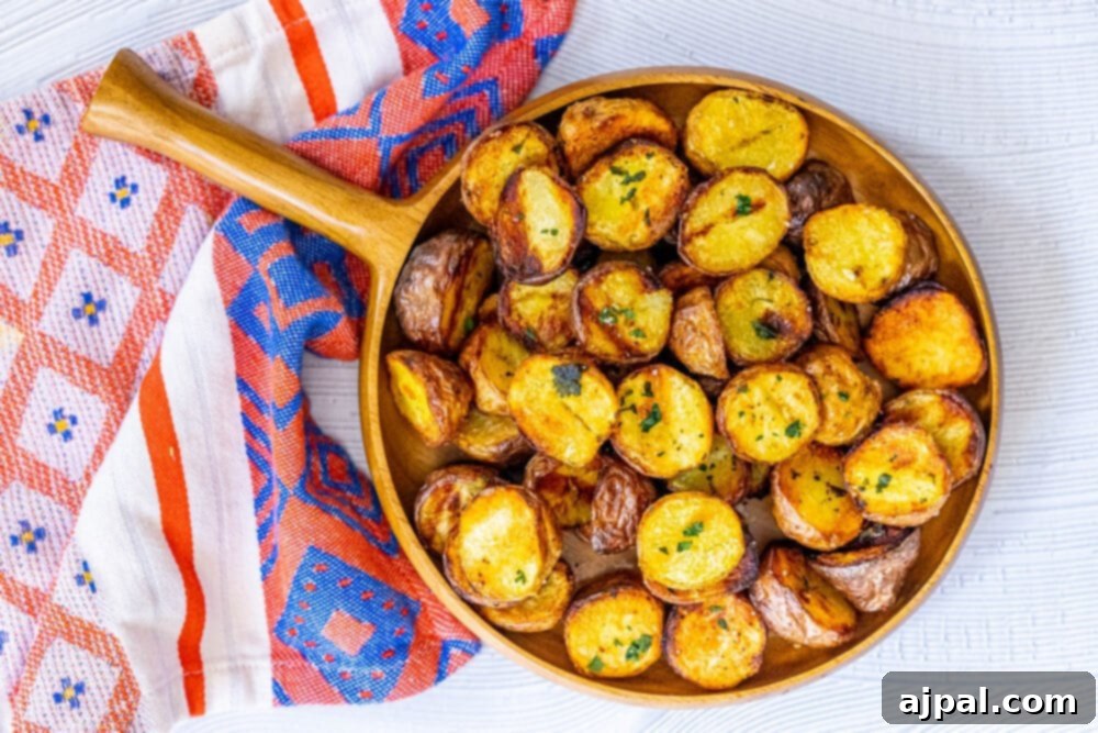 Horizontal shot of beautifully grilled potatoes in a wooden bowl on a wooden table, sprinkled with fresh green herbs.