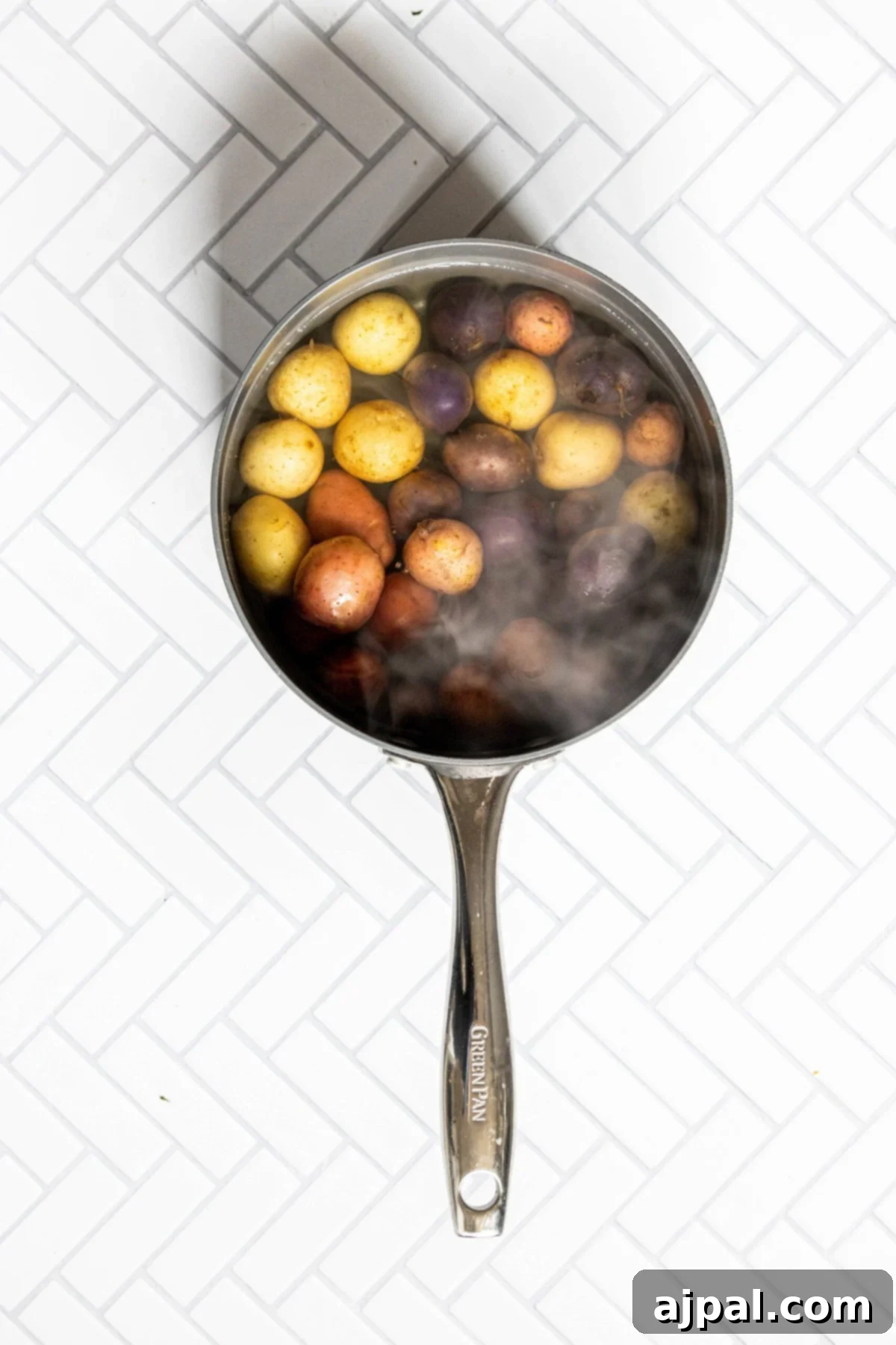 A pot of boiling water with small, whole potatoes submerged, preparing for parboiling.