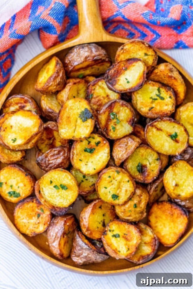 A wooden bowl filled with crispy, golden-brown grilled potatoes, garnished with fresh herbs, sitting on a rustic wooden table.