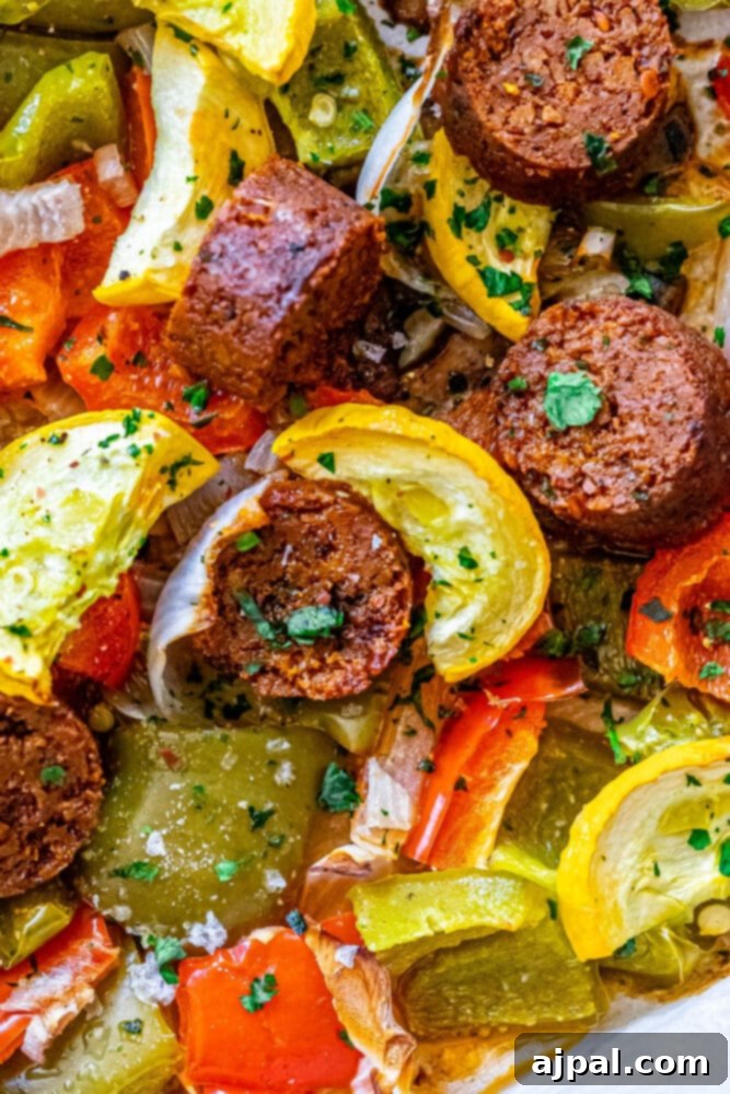 One-Pan Vegan Chorizo Veggie Bake 2 picture of baked vegan chorizo sausage, squash, peppers, onions, and mushrooms on a baking sheet