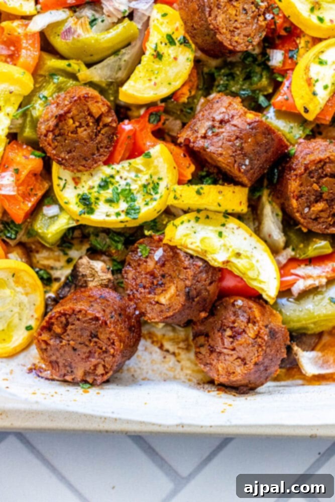 One-Pan Vegan Chorizo Veggie Bake 4 picture of baked vegan chorizo sausage, squash, peppers, onions, and mushrooms on a baking sheet