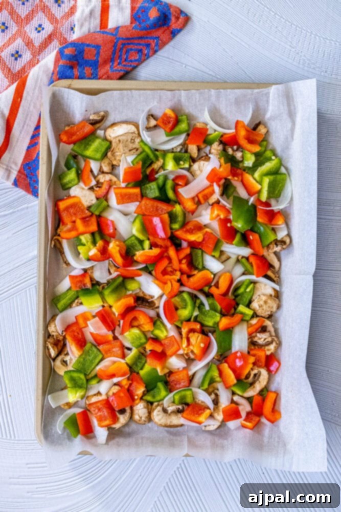 One-Pan Vegan Chorizo Veggie Bake 6 picture of raw sliced vegan chorizo, green onions, onion, shallot, bell peppers, mushrooms on a baking sheet
