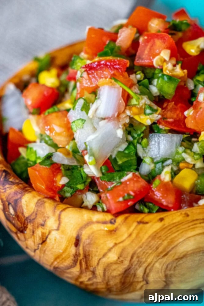 Whip Up Corn Pico De Gallo 7 Picture of corn pico de gallo in a wooden bowl with fresh ingredients scattered around.
