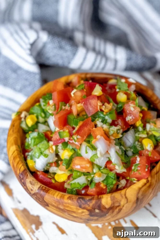 Whip Up Corn Pico De Gallo 3 Salsa with corn and tomatoes – a close-up of Corn Pico de Gallo in a wooden bowl.