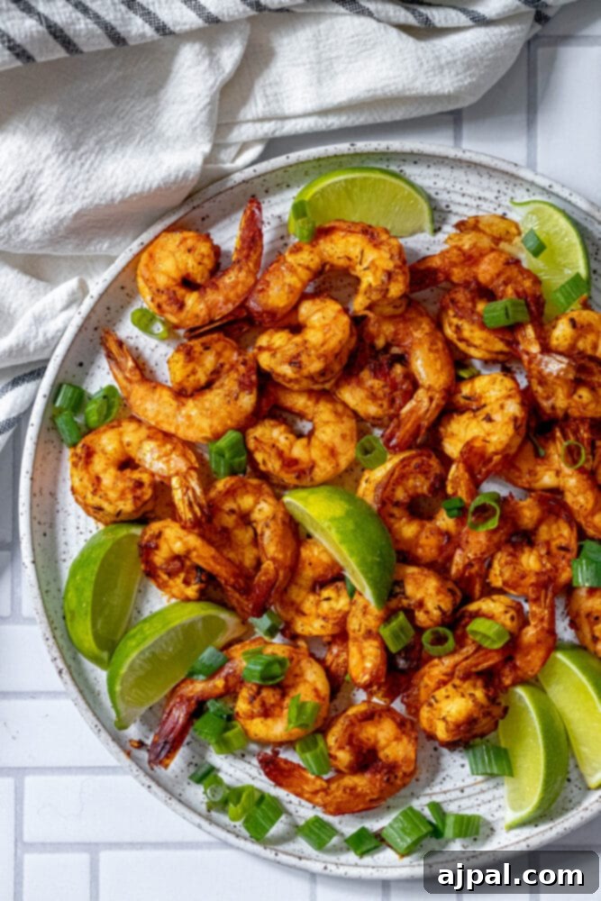 picture of jerk shrimp on a white plate with sliced green onions and limes