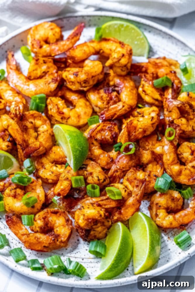 picture of jerk shrimp on a white plate with sliced green onions and limes