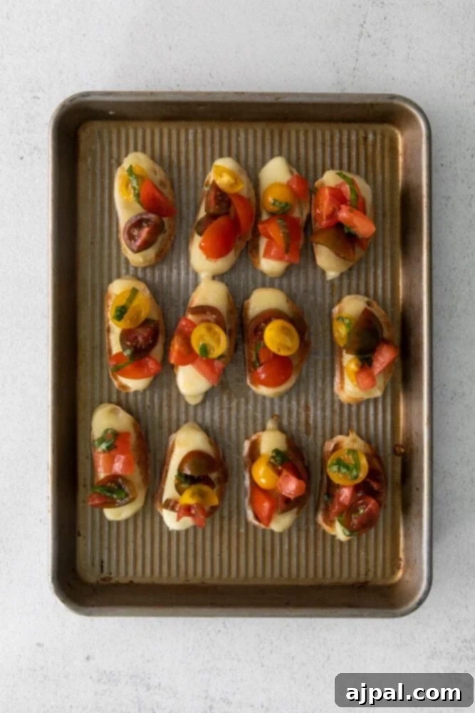 Vibrant Caprese Toasts 6 Baked bread with melted cheese topped with a vibrant diced tomato and basil mixture, presented beautifully on a baking sheet.