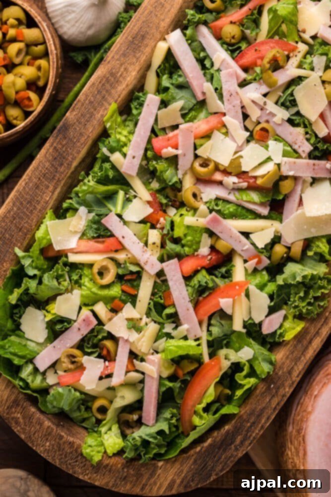 Crisp Julienne Kale Salad 6 picture of julienne kale salad with meat cheese and vegetables with a Mediterranean dressing in a wood bowl on a table