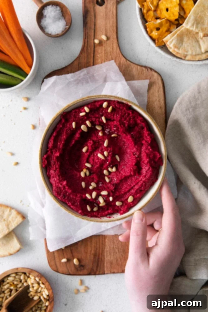 Vibrant Roasted Beet Hummus 2 A vibrant bowl of homemade beet hummus displayed on a cutting board.