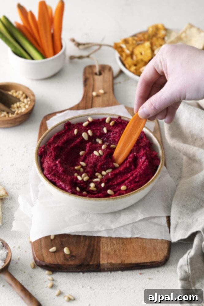 Vibrant Roasted Beet Hummus 8 An appetizing presentation of roasted beet hummus paired with fresh carrots on a rustic wooden cutting board.