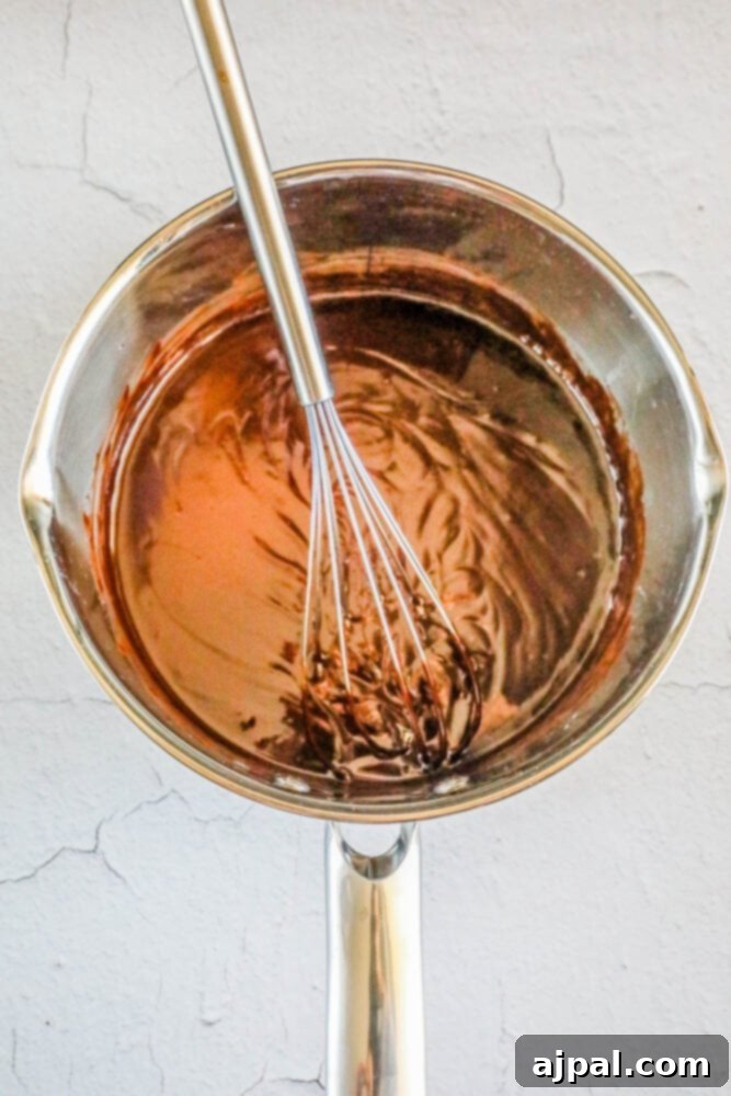Easter Egg Nest Delights 7 Melted chocolate, butter, and corn syrup are combined in a pan, creating a smooth and glossy coating for the cookies.