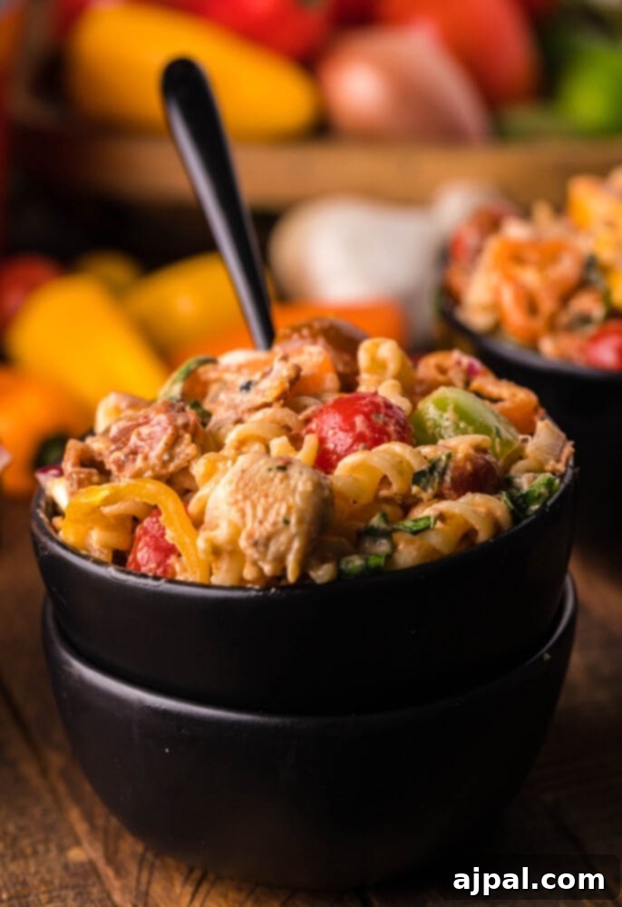 Velvet Chicken Bacon Pasta Salad 2 A vibrant bowl of creamy chicken bacon pasta salad, brimming with tender chicken, crispy bacon, and colorful vegetables, all coated in a rich dressing.
