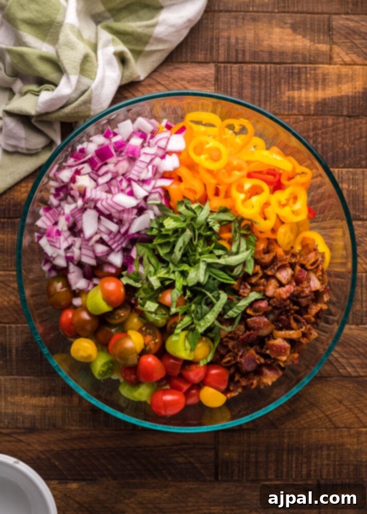 Velvet Chicken Bacon Pasta Salad 8 Chopped crispy bacon and fresh, colorful vegetables like cherry tomatoes and sweet peppers in a bowl.