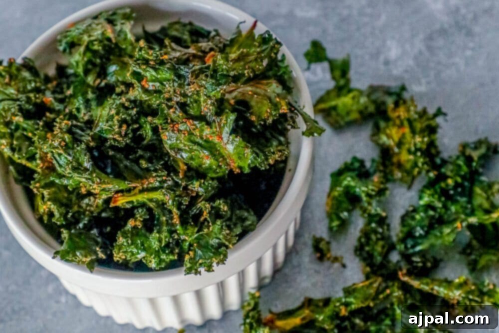 A pristine white bowl filled with perfectly crispy and vibrant green kale chips, presented elegantly on a rustic wooden surface.