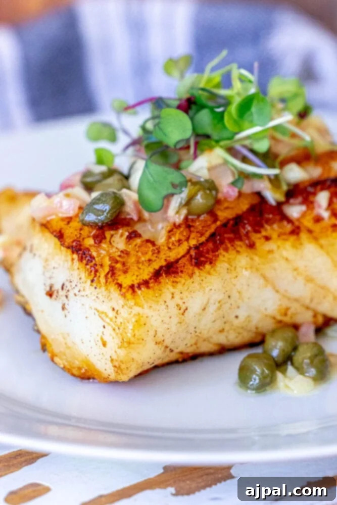 Pan-Seared Chilean Seabass with Lemon Caper Butter 2 Pan-fried Chilean seabass with lemon caper butter sauce on top, served on a pristine white plate.