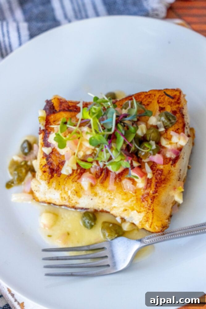 Pan-Seared Chilean Seabass with Lemon Caper Butter 11 A Lemon Caper Butter Chilean Seabass on a plate with a fork, emphasizing its appetizing presentation.
