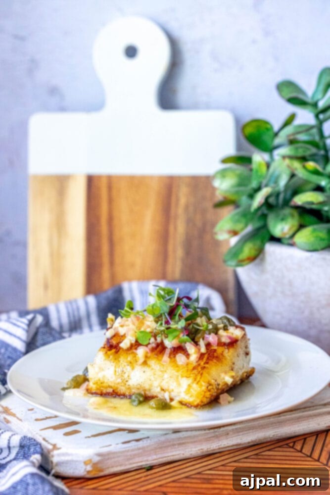 Pan-Seared Chilean Seabass with Lemon Caper Butter 12 A plate with a glistening piece of Chilean Seabass, generously topped with lemon caper butter.