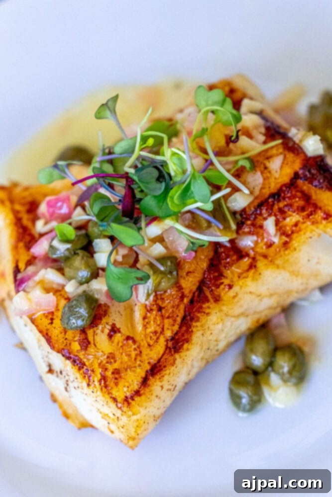 Pan-Seared Chilean Seabass with Lemon Caper Butter 4 A close-up of a lemon caper butter Chilean seabass dish, showcasing the flaky fish on a white plate.