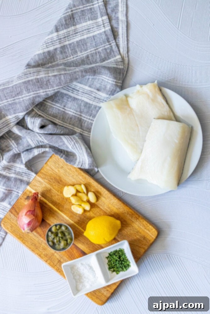 Pan-Seared Chilean Seabass with Lemon Caper Butter 5 Selection of ingredients for lemon caper Chilean seabass: fish fillets, garlic, shallot, lemon, salt, capers, and herbs on a table.