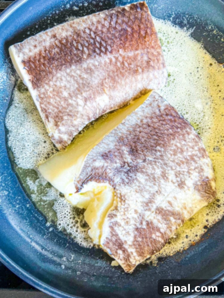 Pan-Seared Chilean Seabass with Lemon Caper Butter 6 Chilean seabass fillets pan-frying in butter on a stove, achieving a perfect golden brown.