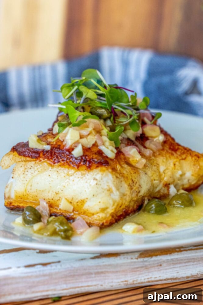 Pan-Seared Chilean Seabass with Lemon Caper Butter 10 Chilean seabass with lemon caper butter sauce and olives on a plate with a fork.