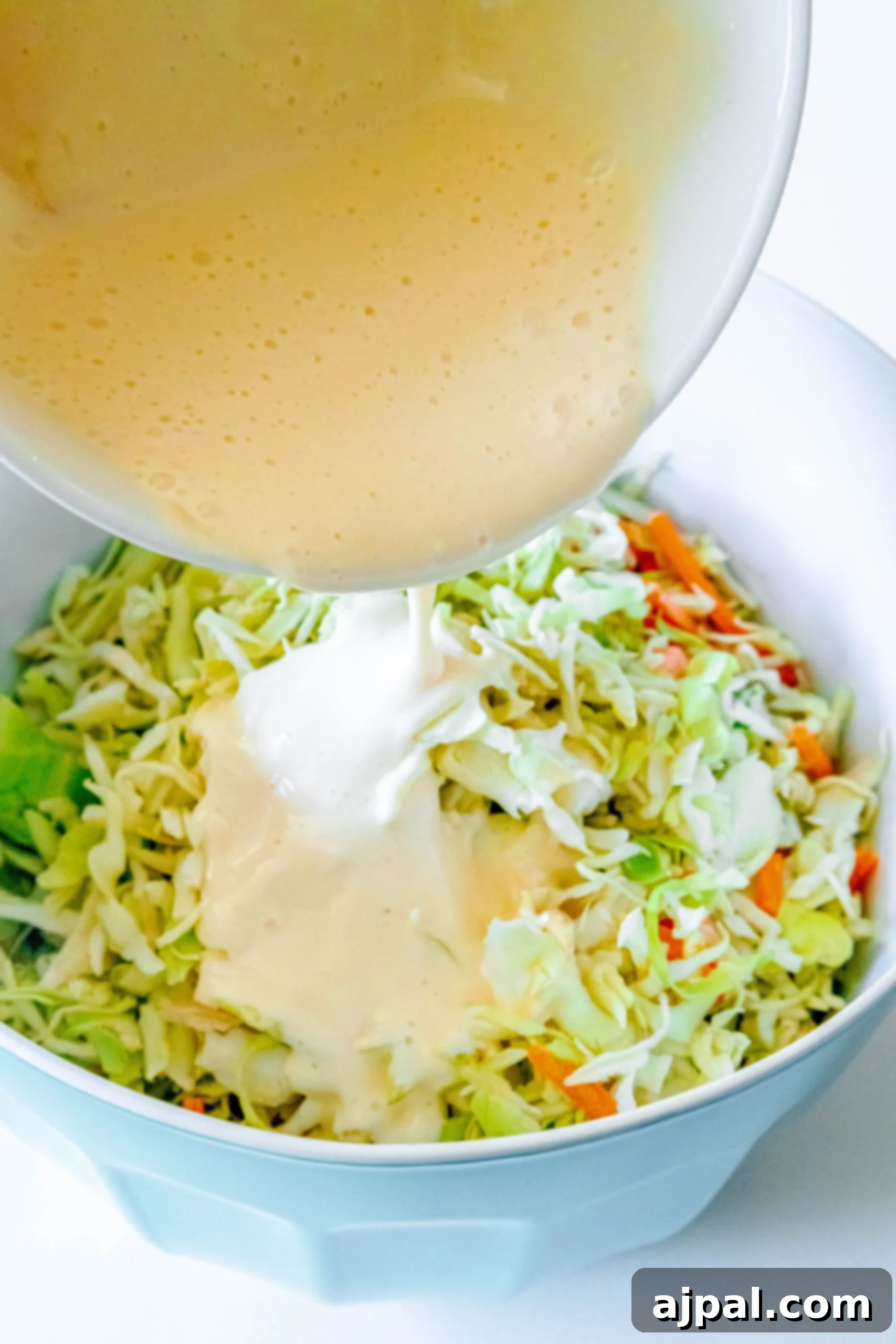 Quick & Easy 4-Ingredient Coleslaw 6 Pouring creamy coleslaw dressing over a bowl of fresh shredded cabbage and carrots.