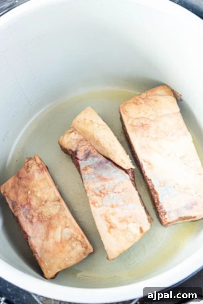 Three pieces of beef short ribs are being cooked in an Instant Pot.