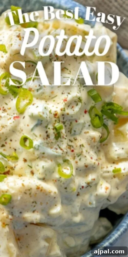 Simple & Scrumptious Potato Salad 13 Picture of creamy potato salad with green onions and cracked pepper in a blue bowl, photographed from above.