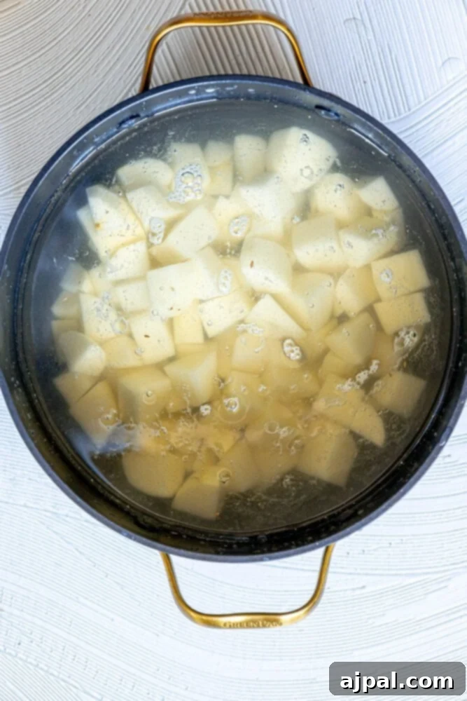 Simple & Scrumptious Potato Salad 6 Picture of potatoes boiling in water in a saucepan on the stove.