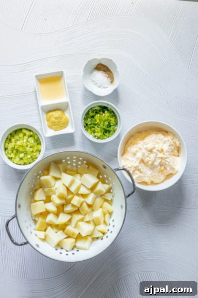 Simple & Scrumptious Potato Salad 7 Picture of boiled potatoes, mayonnaise, onions, celery, mustard, apple cider vinegar, and seasonings laid out on a table.