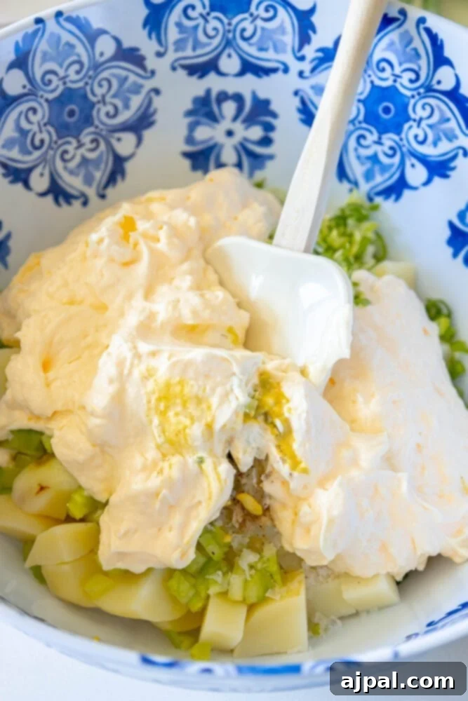 Simple & Scrumptious Potato Salad 8 Picture of potato salad being mixed in a large bowl with a spoon, showing the creamy texture.