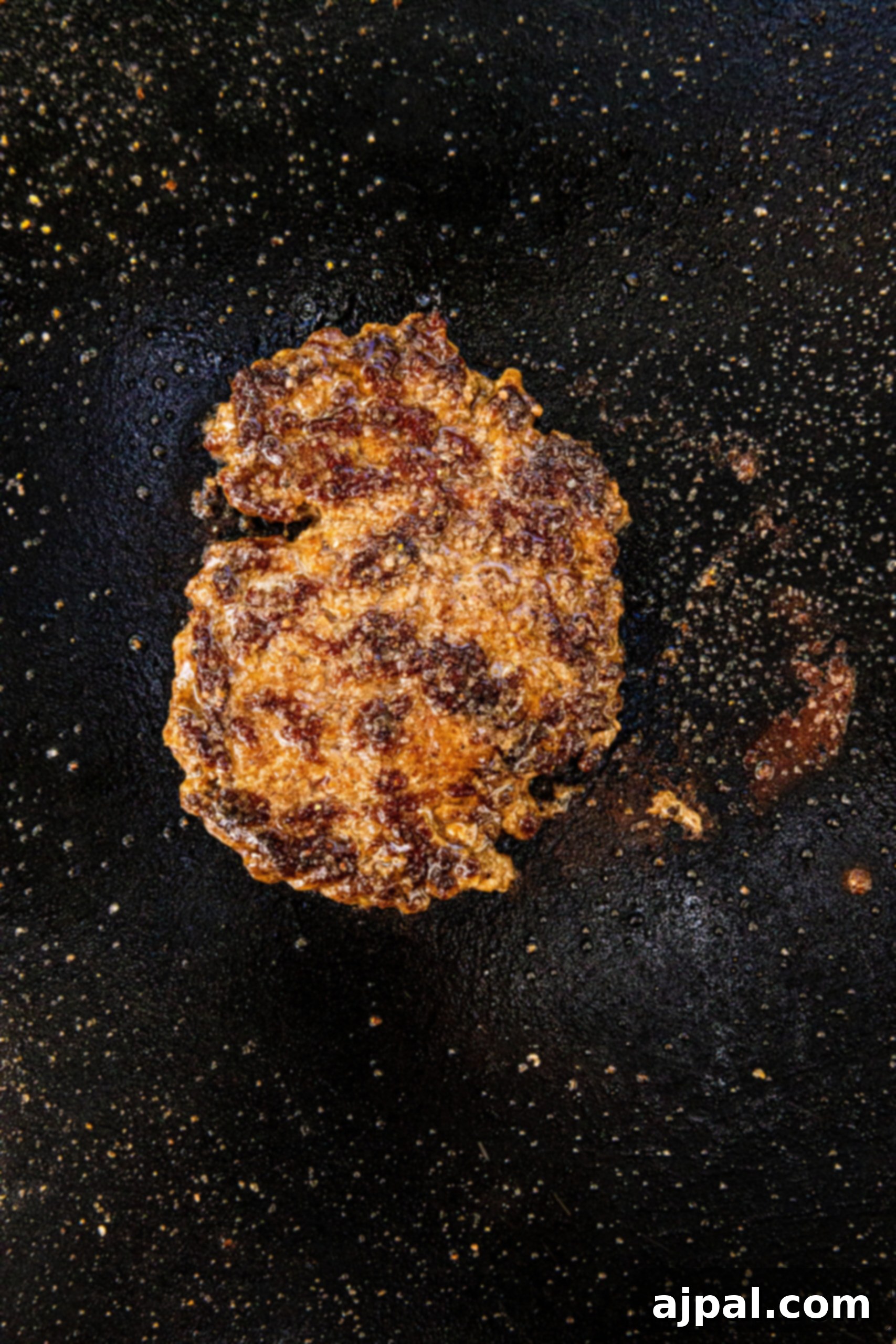 picture of browned smashed burger patty cooking on a griddle