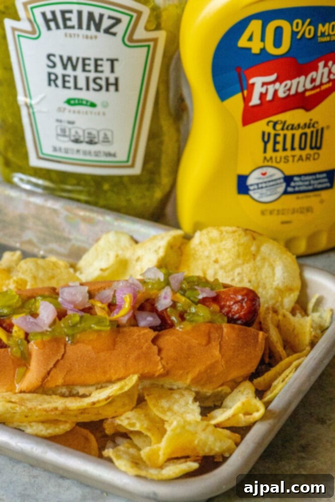 picture of bacon-wrapped hot dog in a bun topped with mustard, relish, and onions